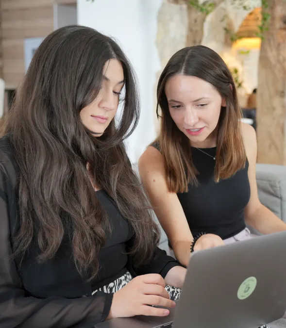 Zwei Teammitglieder einer Agentur arbeiten gemeinsam an einem Laptop an einer Software-Entwicklung.